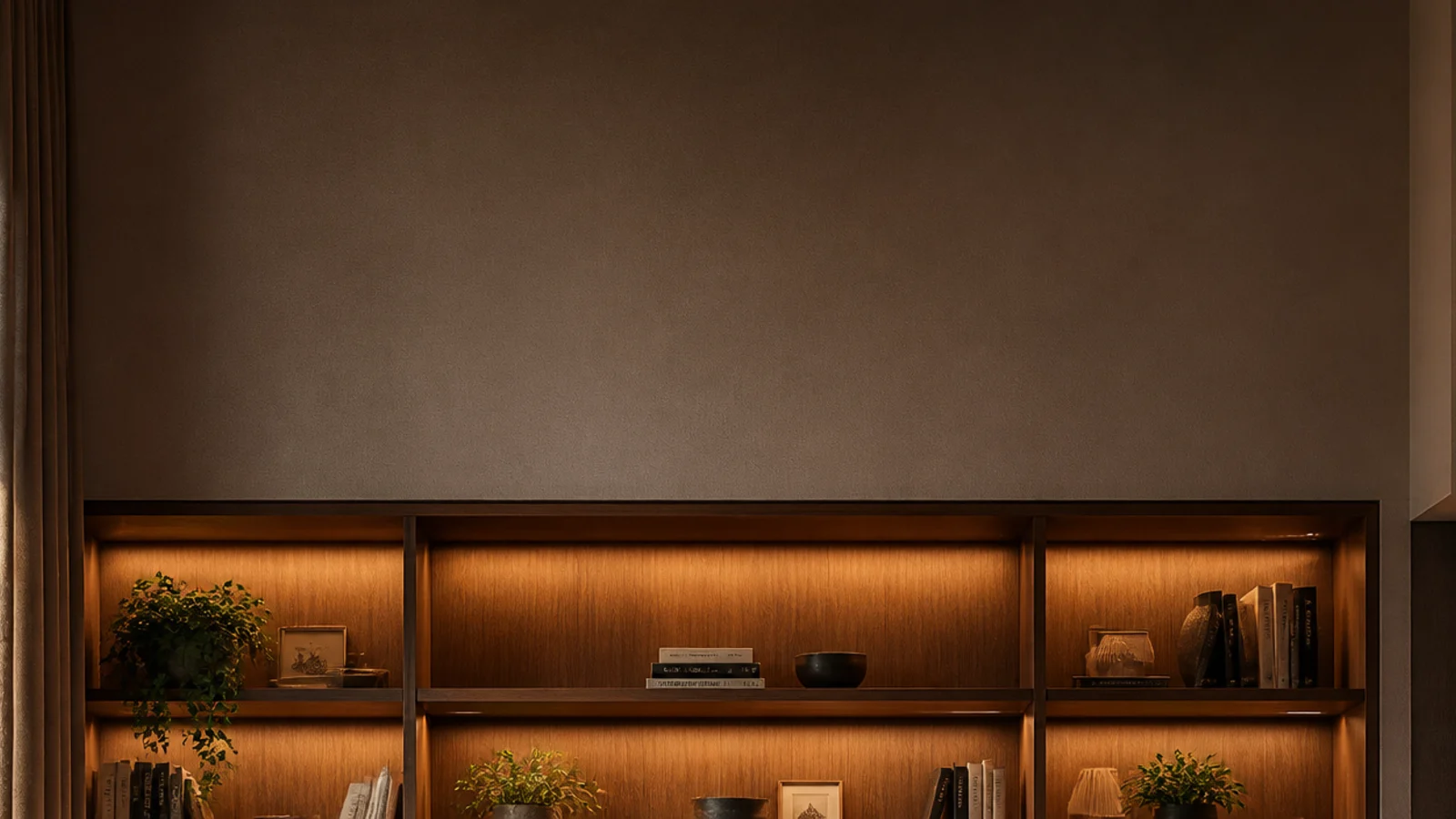 tall view of a styled wall unit with lit bays books and hidden storage