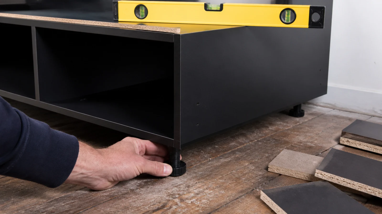 adjustable cabinet foot being turned to level a media carcass