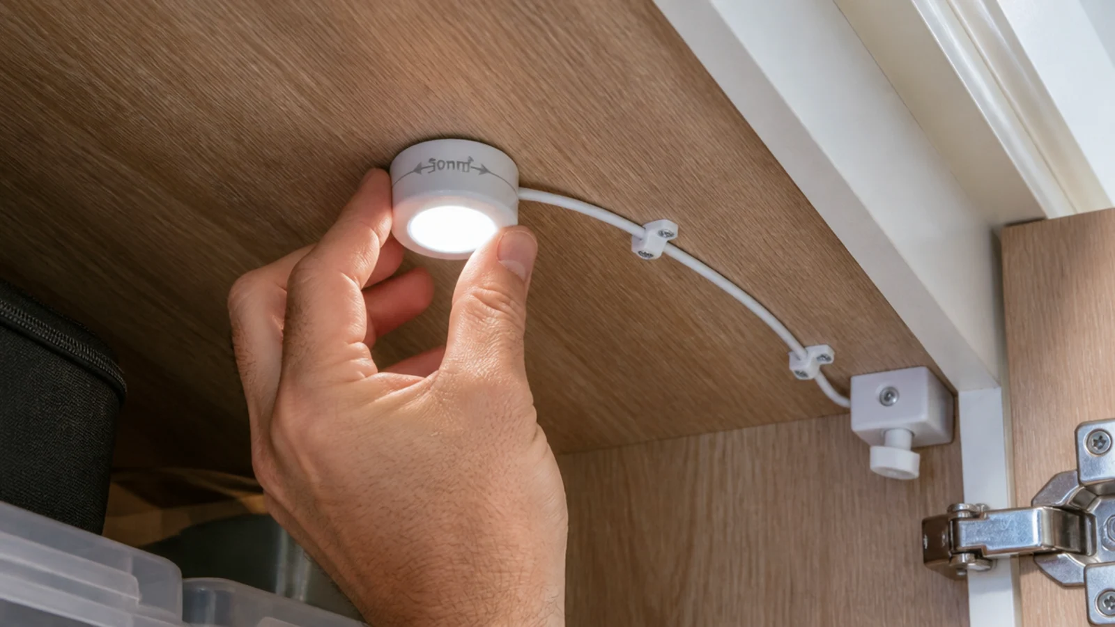 small puck light being fitted to a stair soffit inside storage