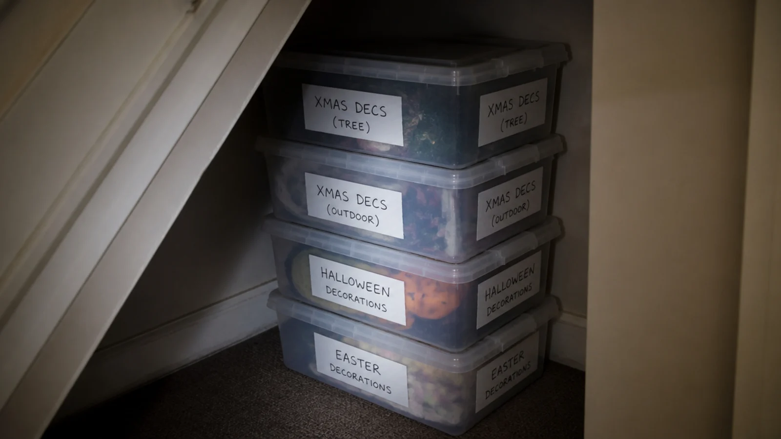 clear lidded boxes labelled on two faces stacked in a stair recess