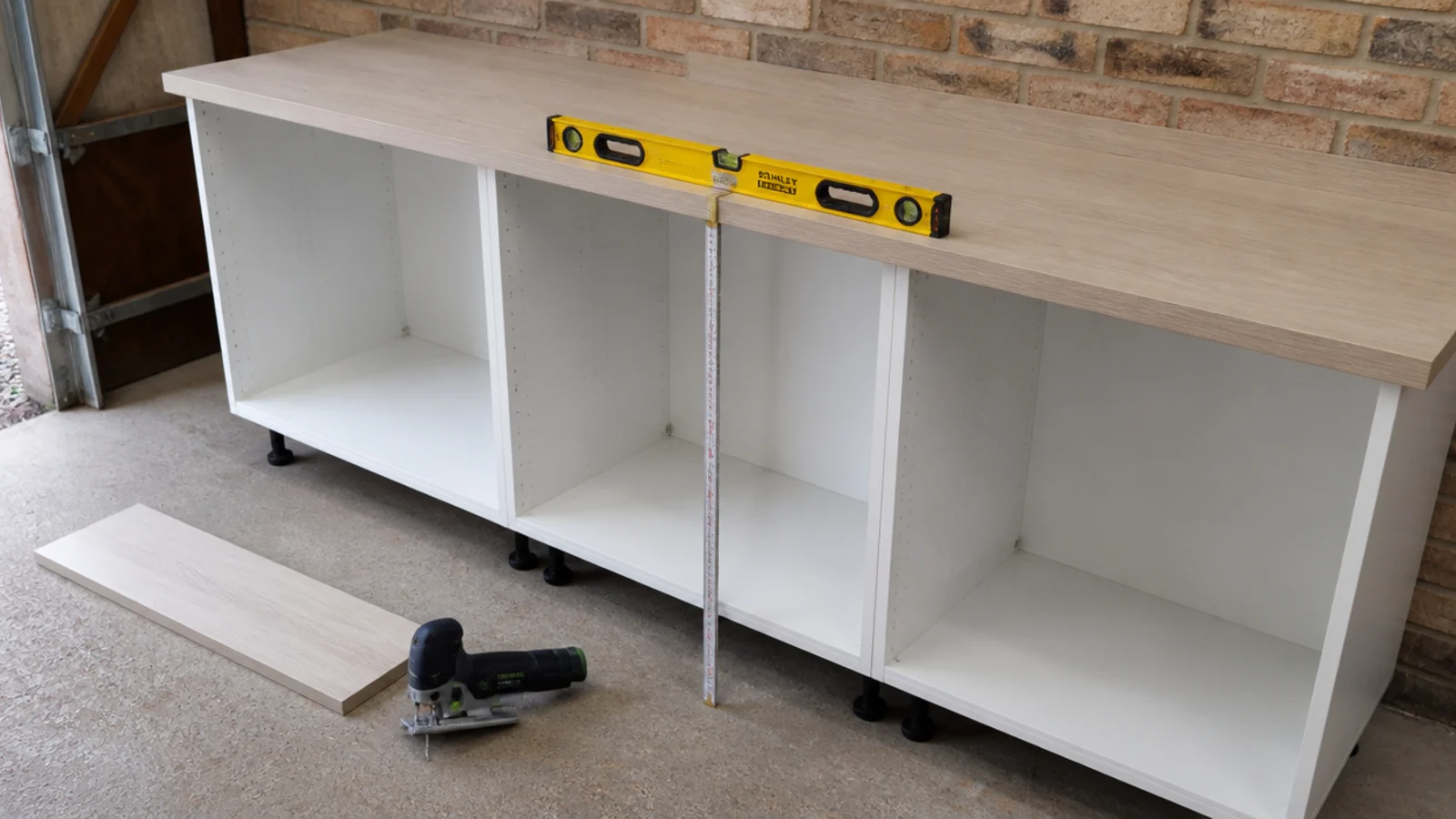 laminate worktop being levelled over new cabinets in a garage utility