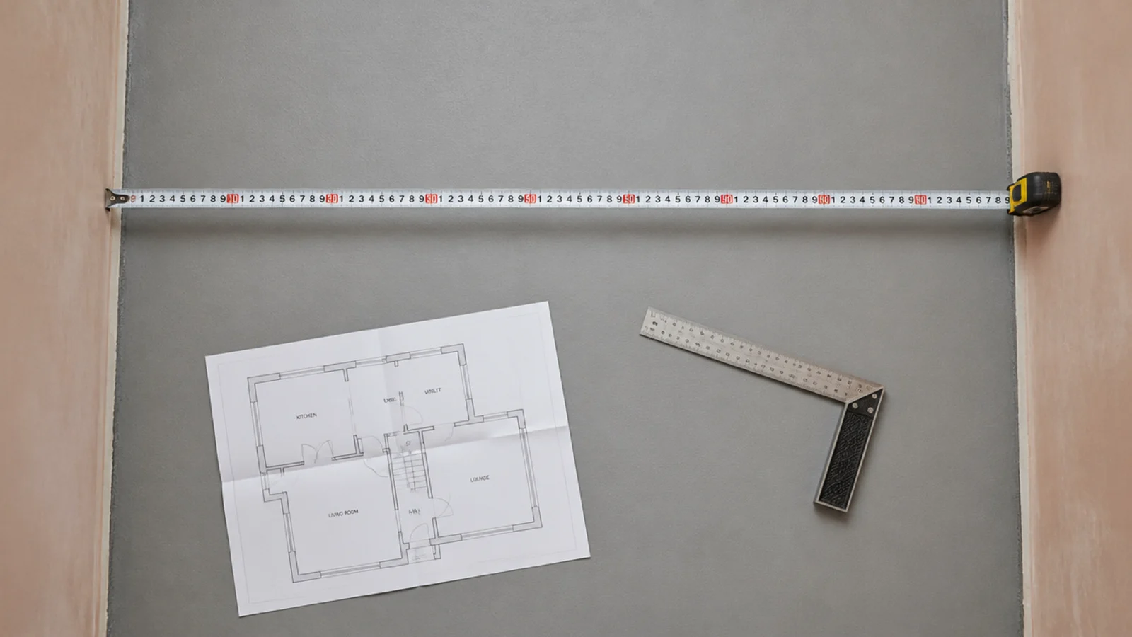 tape measure stretched across a slim laundry floor between two plastered walls