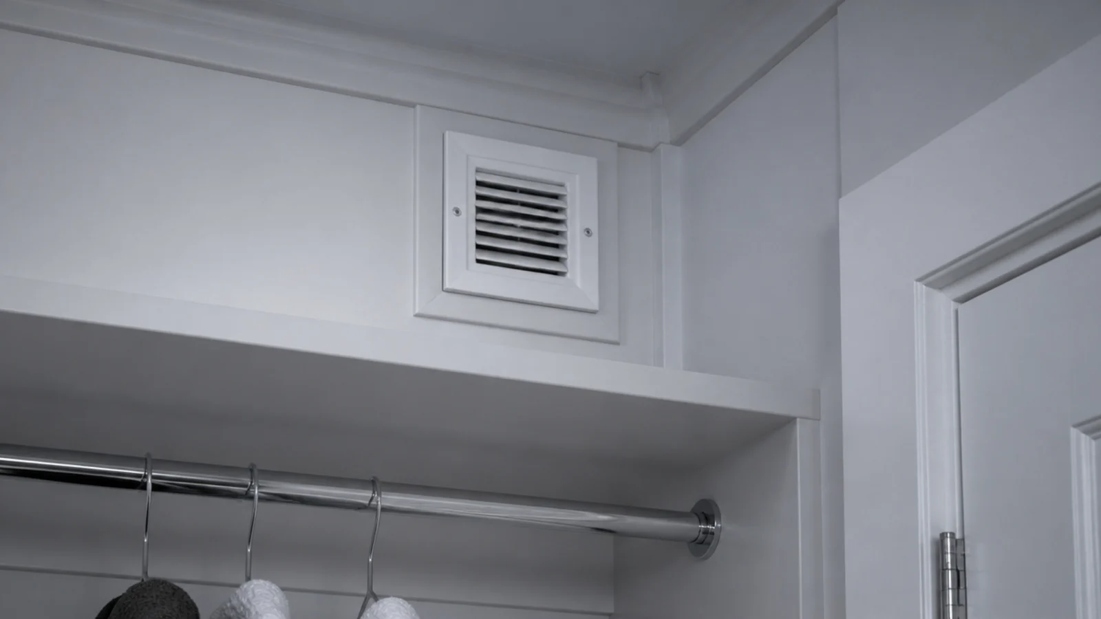 small white grille set high in a laundry cupboard wall near the ceiling