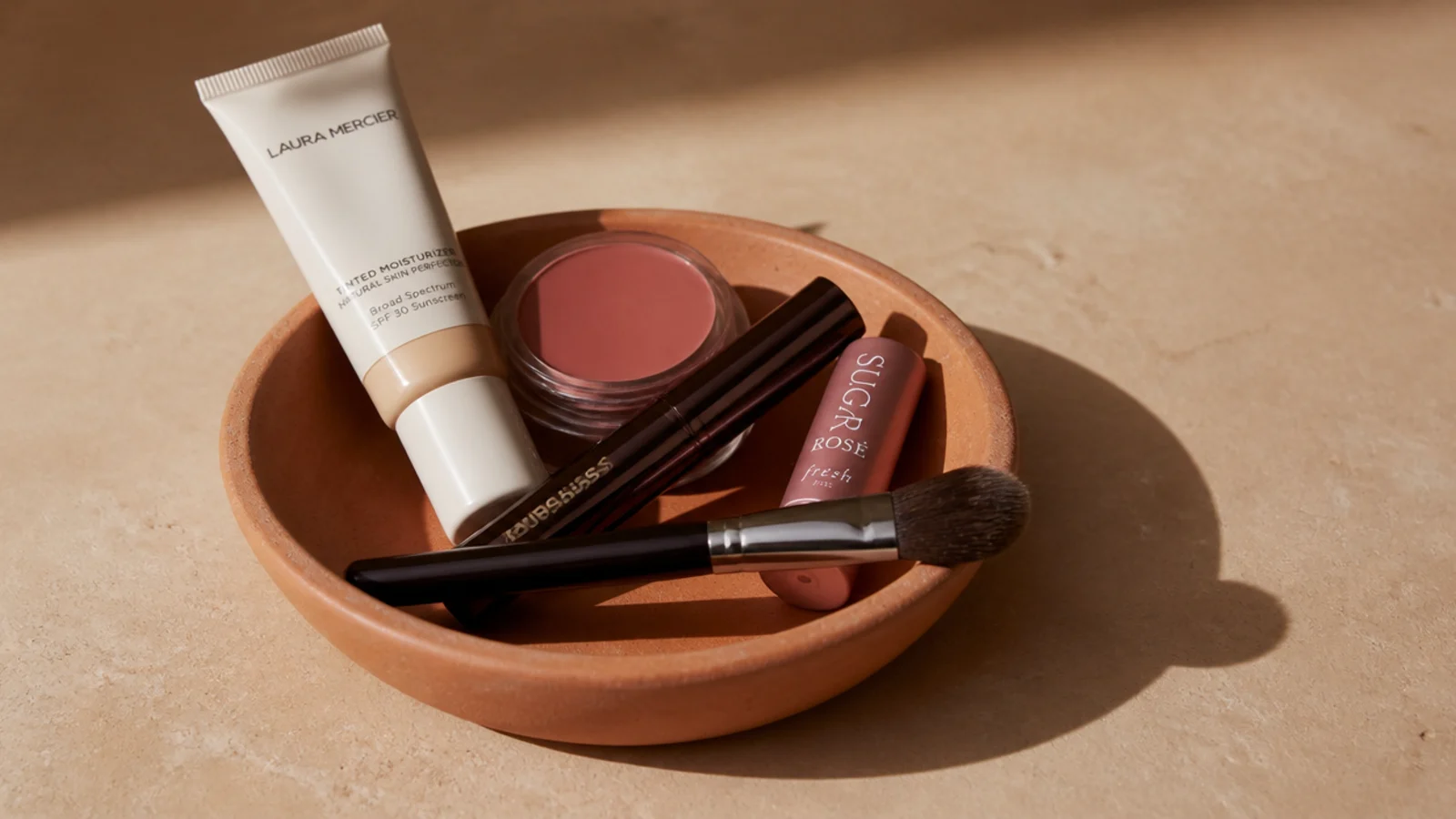 five everyday makeup products grouped in a small clay dish