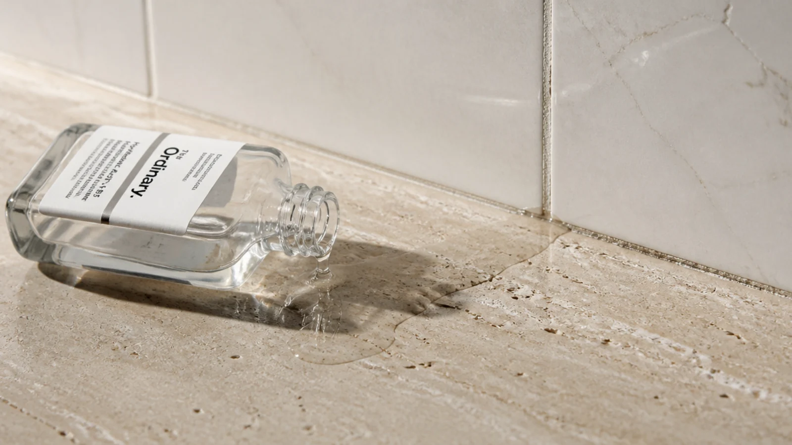 spilled serum running across a bare vanity counter with no tray edge