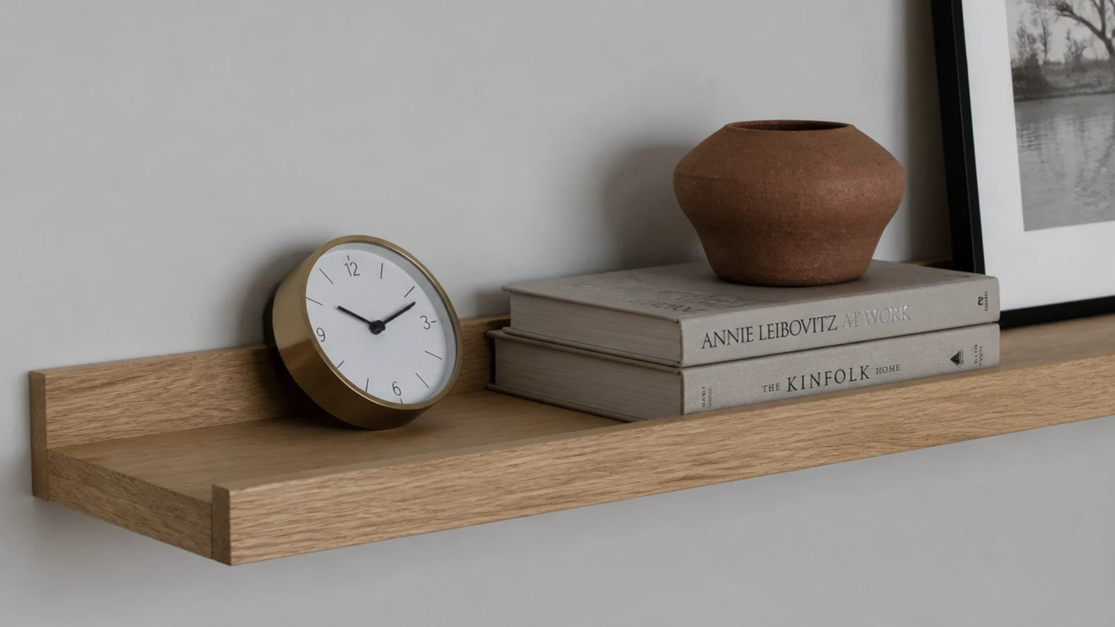 clock leaning against the wall on a wide picture ledge