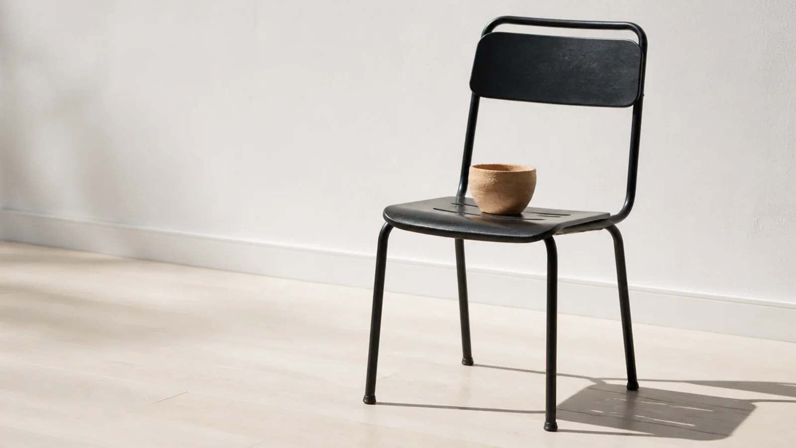 black metal chair standing alone on a very pale timber floor