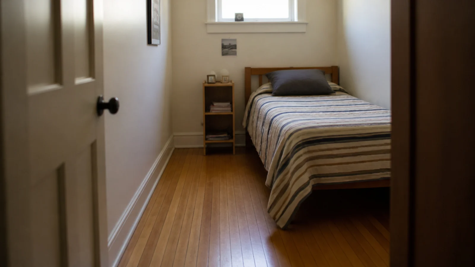narrow oak strips filling a very small bedroom with many board runs