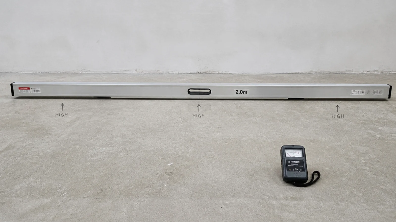 straightedge and moisture meter checking a bare concrete subfloor surface