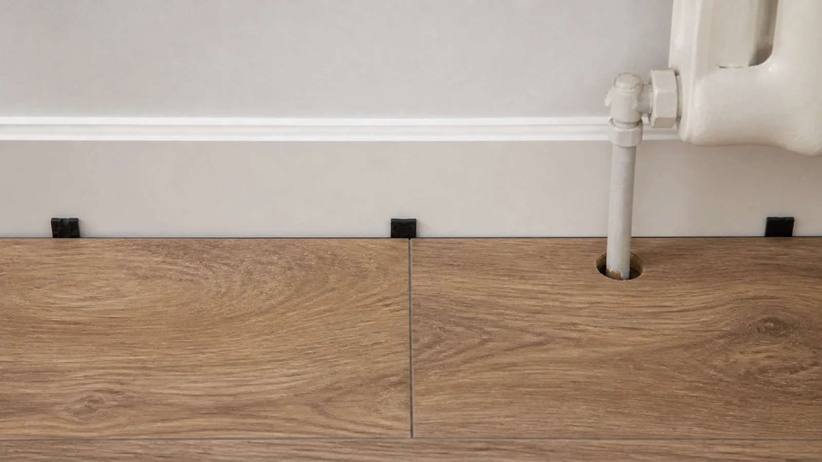 small perimeter gap held open between vinyl planks and a bedroom wall
